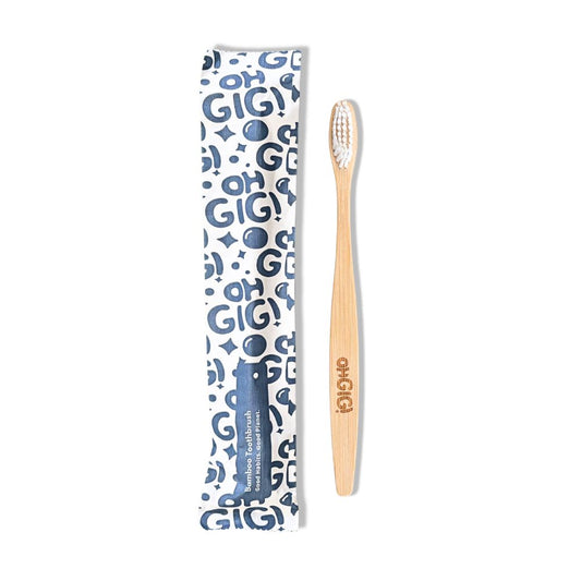 A bamboo toothbrush with a light wood handle and white bristles, shown next to its blue and white patterned packaging sleeve on a plain white background.