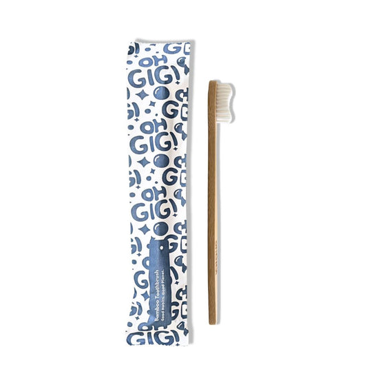 A bamboo toothbrush with white bristles next to its white and blue patterned protective sleeve on a plain white background.